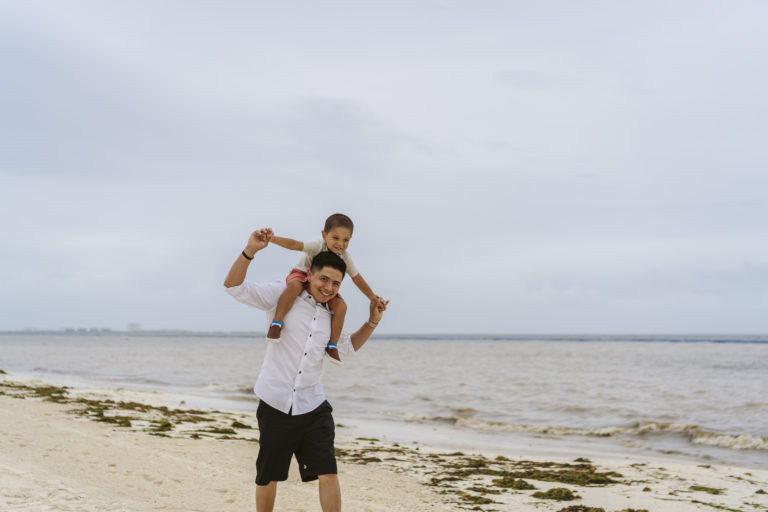 son on father's shoulders at beach