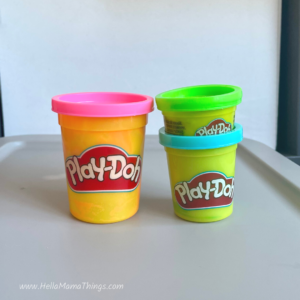 3 Play Doh containers of different sizes, pink, blue, and green