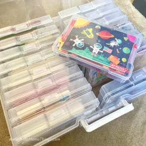 Box of puzzles organized in plastic containers, one laying on top